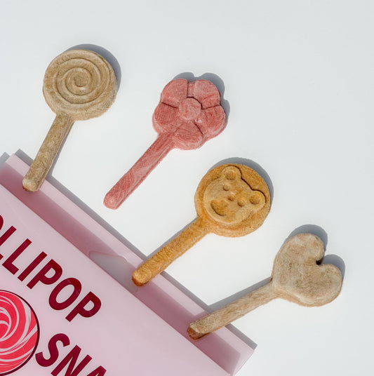 Four lollipop snacks on sticks. The lollipops are shaped like a circle, flower, bear, and heart. The lollipops are all different colors. The lollipops are on a pink background with the words 'Lollipop Snacks'.
