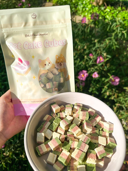 The bag has the text &#39;Petit Pawtisserie&#39; and &#39;Pet Cake Cubes&#39; on it. The bag is filled with small, square, multi-colored pet treats. The treats are in a white bowl. Petit Pawtisserie freeze-dried cake cube pet treats for cats and dogs – soft bite sized snacks with 3 layers of flavor