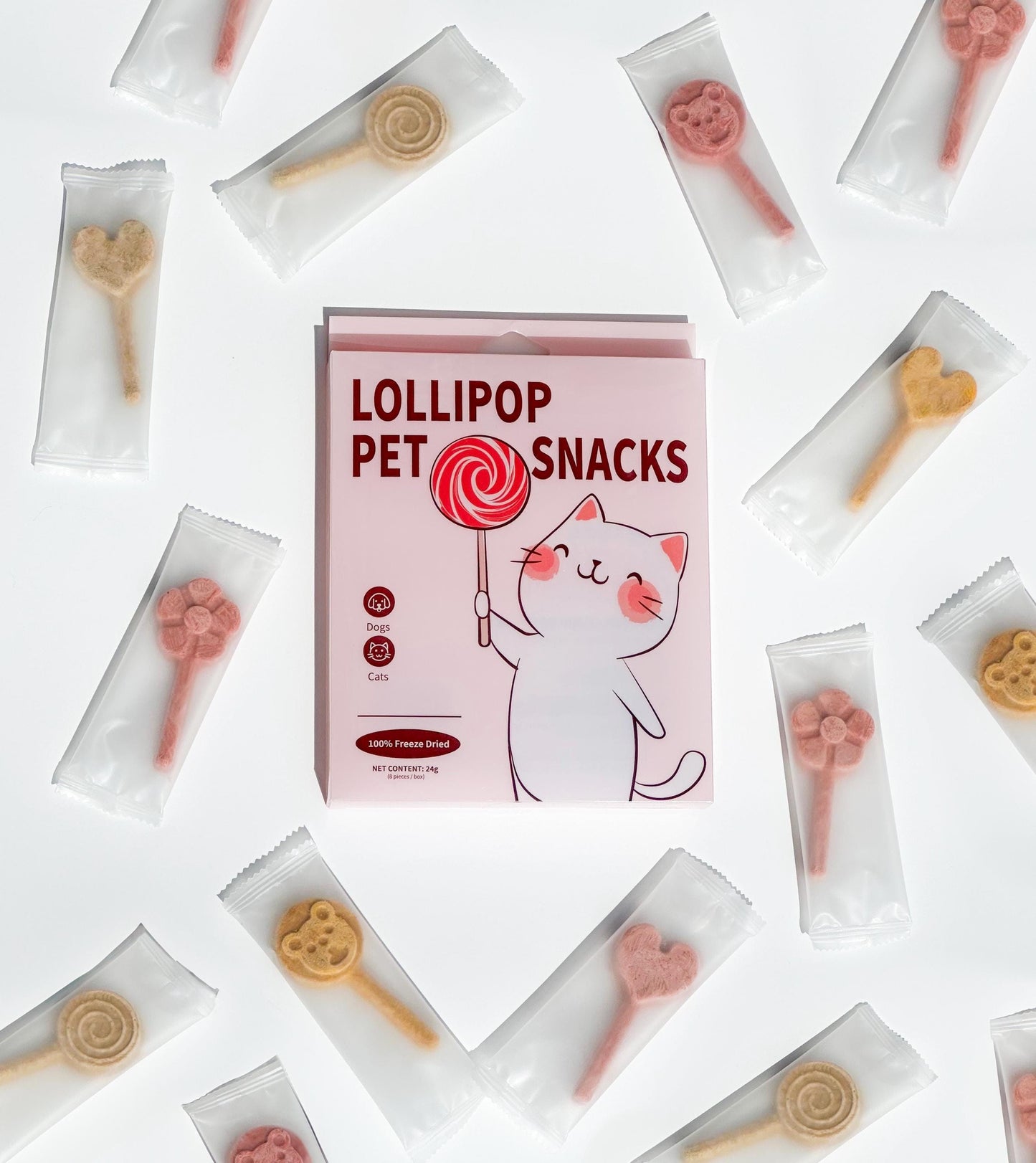 A box of lollipop pet snacks with a cartoon cat holding a red lollipop. The box is pink with white text that reads &#39;Lollipop Pet Snacks&#39;. The box is surrounded by individual packages of the snacks, which are in various shapes, including hearts, flowers, bears and lollipops. The snacks are in different colors, including pink, red, and yellow. The text on the box also reads 100% Freeze Dried.